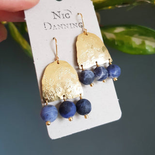 Glowing gold earrings with semi precious sodalite beadwork. 'Titans Astrape' ethical hand beaten brass earrings by Nic Danning Jewellery.