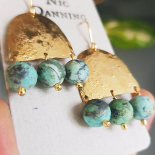 Glowing gold earrings with semi precious turquoise beadwork. 'Titans Gaia' ethical hand beaten brass earrings by Nic Danning Jewellery.