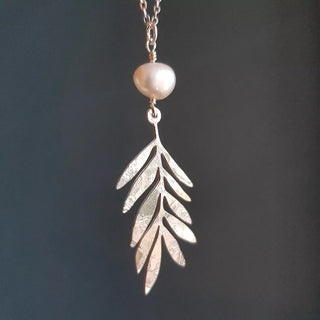 Shimmering silver necklace in a botanical leaf design with natural freshwater pearl bead. 'Gossamer Athena' ethical hand beaten stainless steel and freshwater pearl necklace by Nic Danning Jewellery.